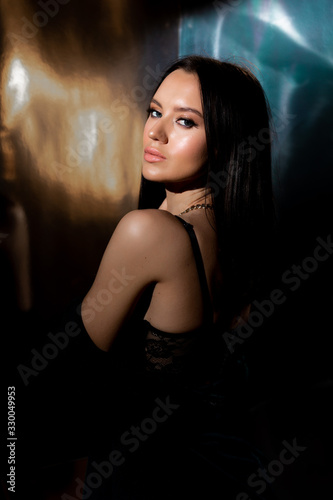 Studio photo of pretty brunette woman in twilight in bra looking over his shoulder