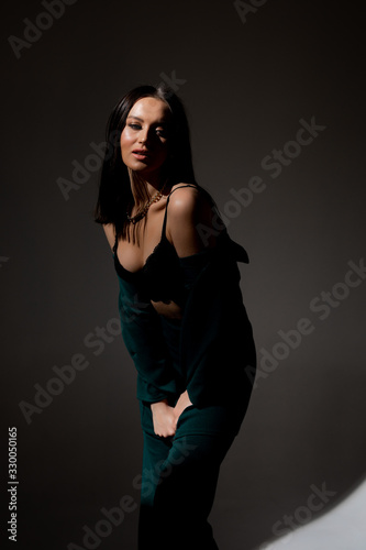 Studio photo of pretty brunette woman in twilight in bra looks into the distance