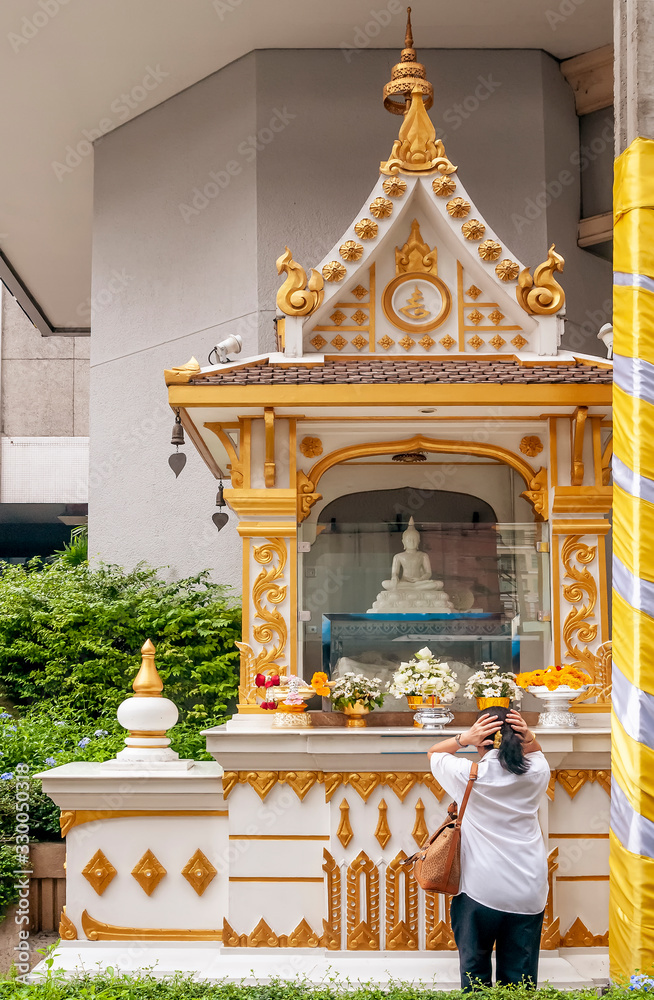 Φωτογραφία A woman prays with her hands on her hair in a small temple on the sides of a bus