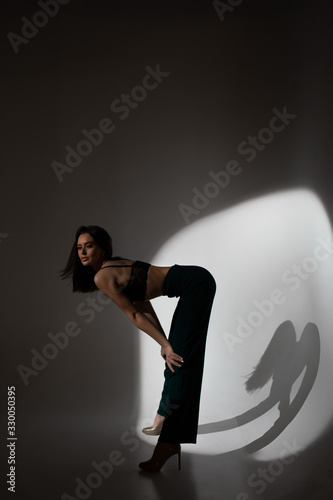 Studio photo of pretty brunette woman in twilight in bra looks into the distance