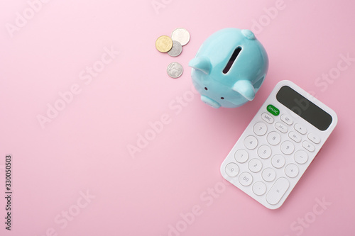 Piggy bank, calculator and coins on pink background photo