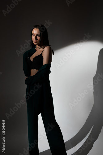 Studio photo of pretty brunette woman in twilight in bra looks into the distance
