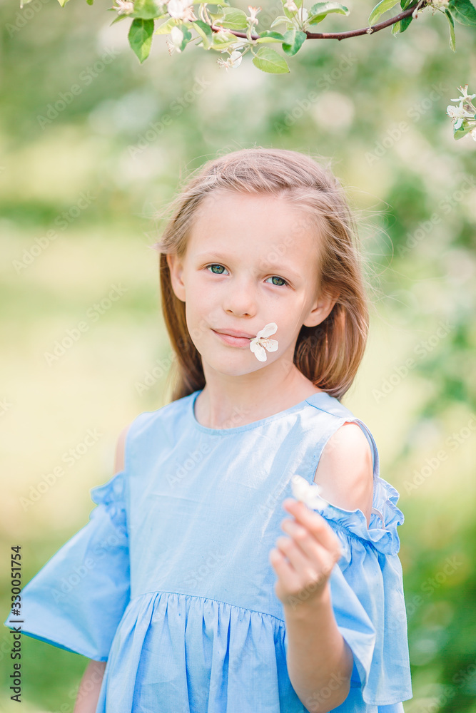 Adorable little girl in blooming apple garden on beautiful spring day Adorable little girl in blooming apple garden on beautiful spring day