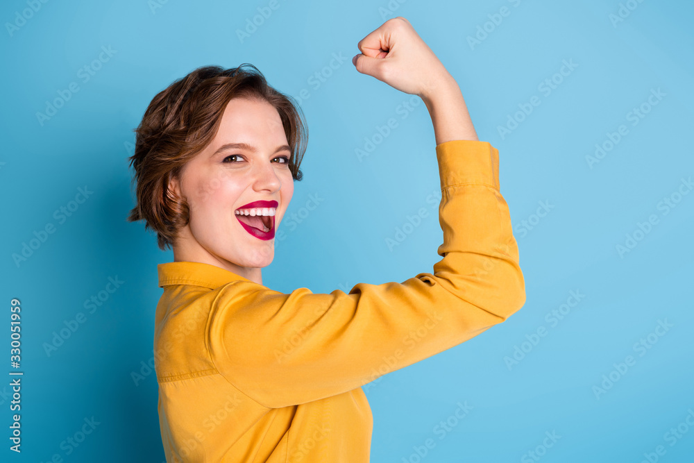 Profile photo of pretty cheerful lady hold raise biceps hand arm show perfect biceps gym training strong powerful woman wear yellow shirt isolated bright blue color background - obrazy, fototapety, plakaty 