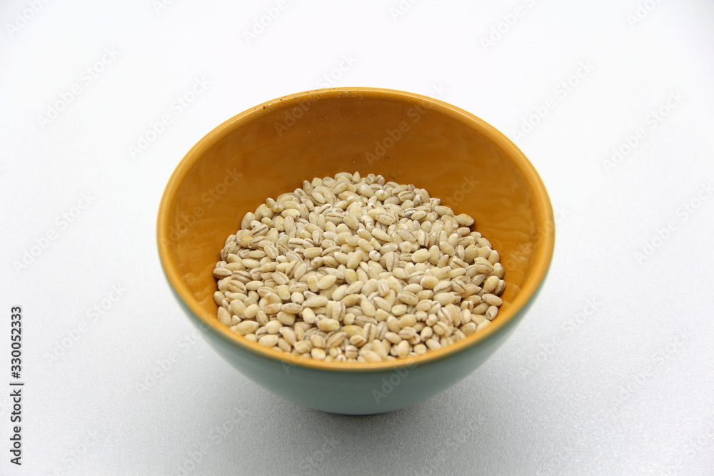 Ceramic bowl with barley on a white background, top view