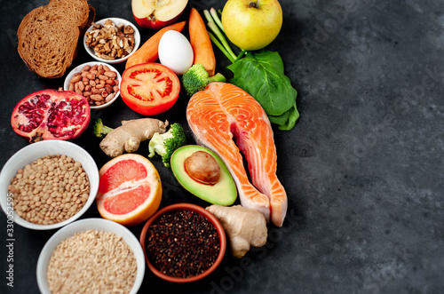 Selection of healthy food: salmon, fruits, seeds, cereals, superfoods, vegetables, leafy vegetables on a stone background   with copy space for your text.Healthy food for people 