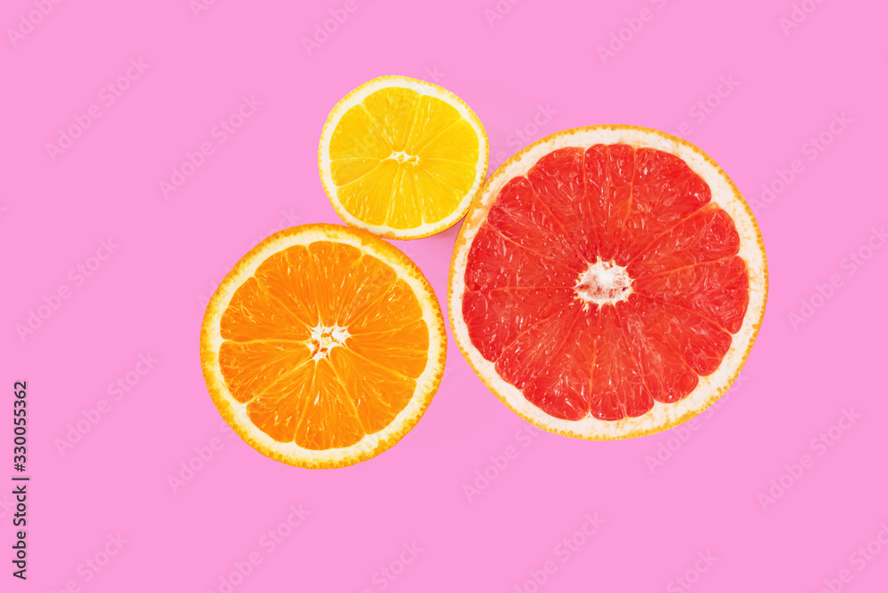 Halves of orange, pink grapefruit and lemon on pink background. Top view of cross section of citrus fruits. Minimal composition. Closeup Halves of orange, pink grapefruit and lemon on pink background. Top view of cross section of citrus fruits. Minimal composition. Closeup