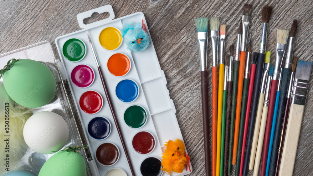 Naklejka premium easter eggs and colorful paints and brushes, bunny