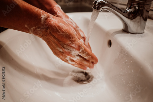 Middle-aged woman washing her hands with soap and water to avoid contagion of the coronavirus. Health risk prevention in old population. Healthcare