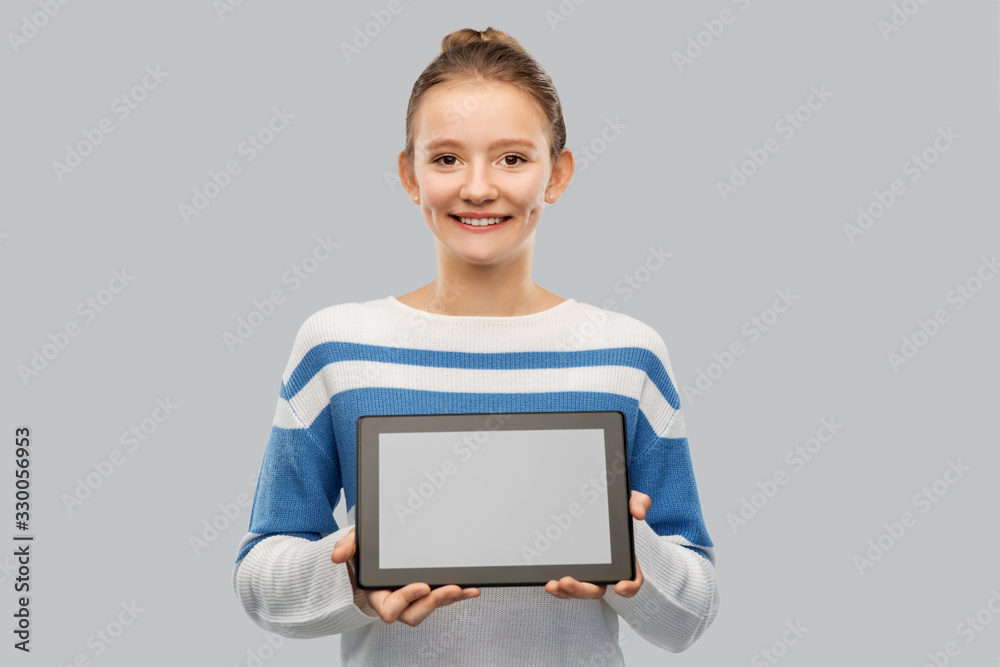 technology and people concept - happy smiling teenage girl in pullover showing tablet pc computer over grey background technology and people concept - happy smiling teenage girl in pullover showing tablet pc computer over grey background