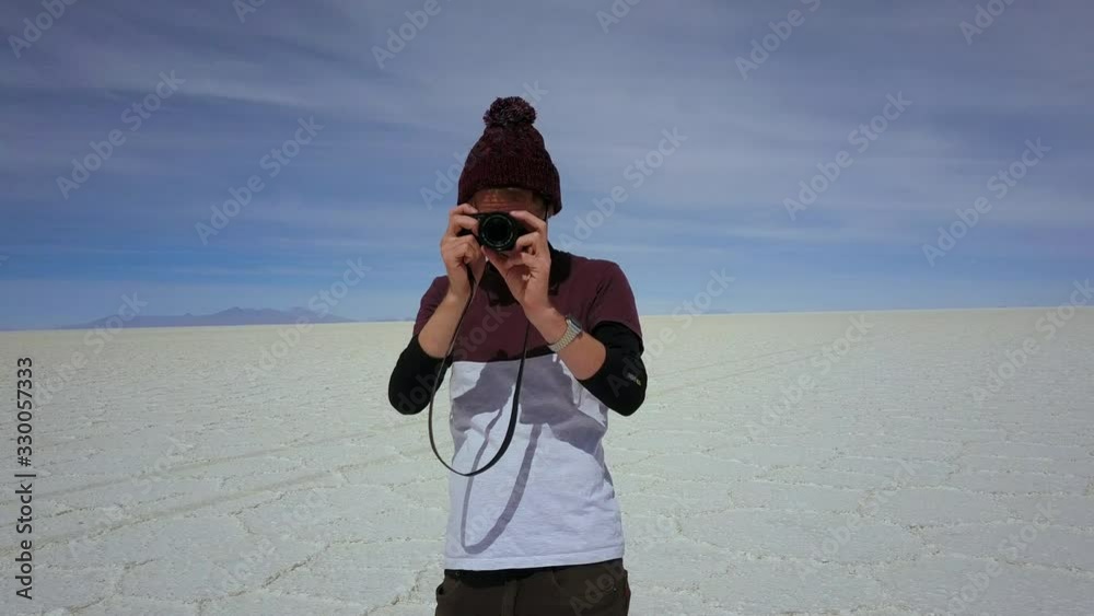 Young traveler taking photo at the Uyuni Salt Flat, Bolivia - aerial tracking away Young traveler taking photo at the Uyuni Salt Flat, Bolivia - aerial tracking away