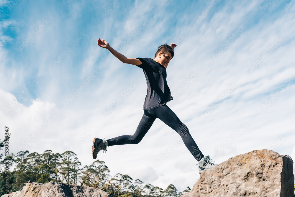 Athlete person jumps between the rocks during a mountain race. Concept of healthy life and sports. Athlete person jumps between the rocks during a mountain race. Concept of healthy life and sports.