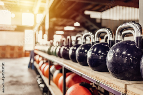 Kettlebells with various colors. Sport equipment in gym. kettlebell on floor background  Fitness training. Shot of a bunch of kettle bells lined up in a row on the floor of a gym