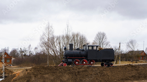 Steam locomotive monument on the village background. museum