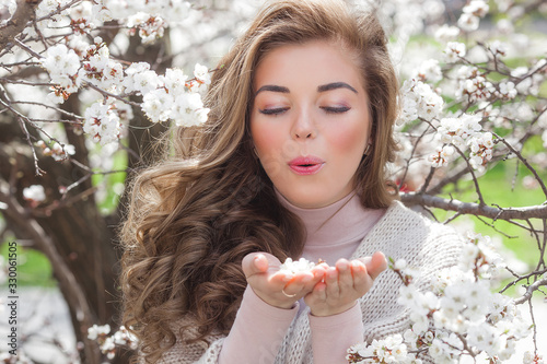 Very attractive young blond woman outdoors. Portrait of beautiful female near the floral tree. Girl with flowers.