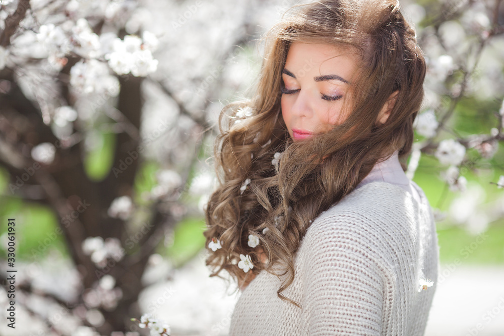 Very attractive young blond woman outdoors. Portrait of beautiful female near the floral tree. Girl with flowers. Very attractive young blond woman outdoors. Portrait of beautiful female near the floral tree. Girl with flowers.