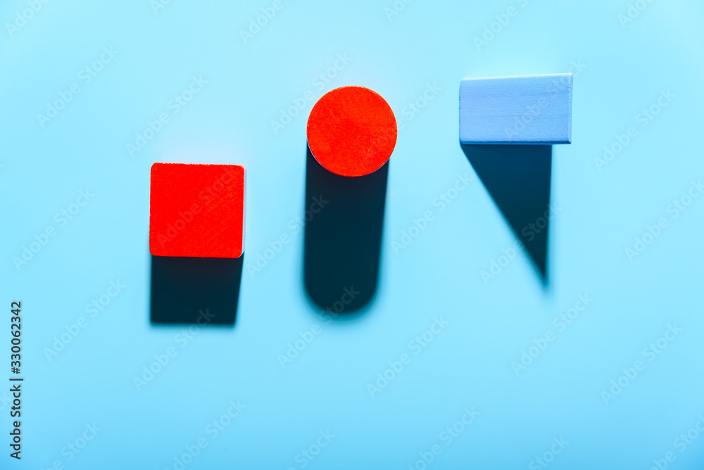 Three geometric figures of solid colors illuminated with hard light on simple blue background. Three geometric figures of solid colors illuminated with hard light on simple blue background.