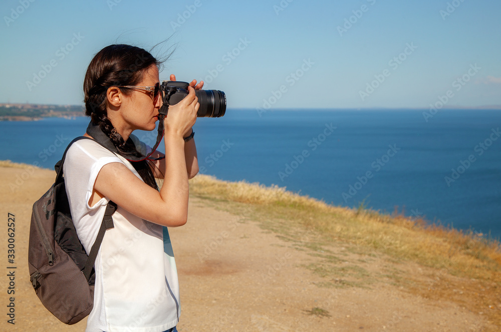 Thin girl with camera in nature, by the sea