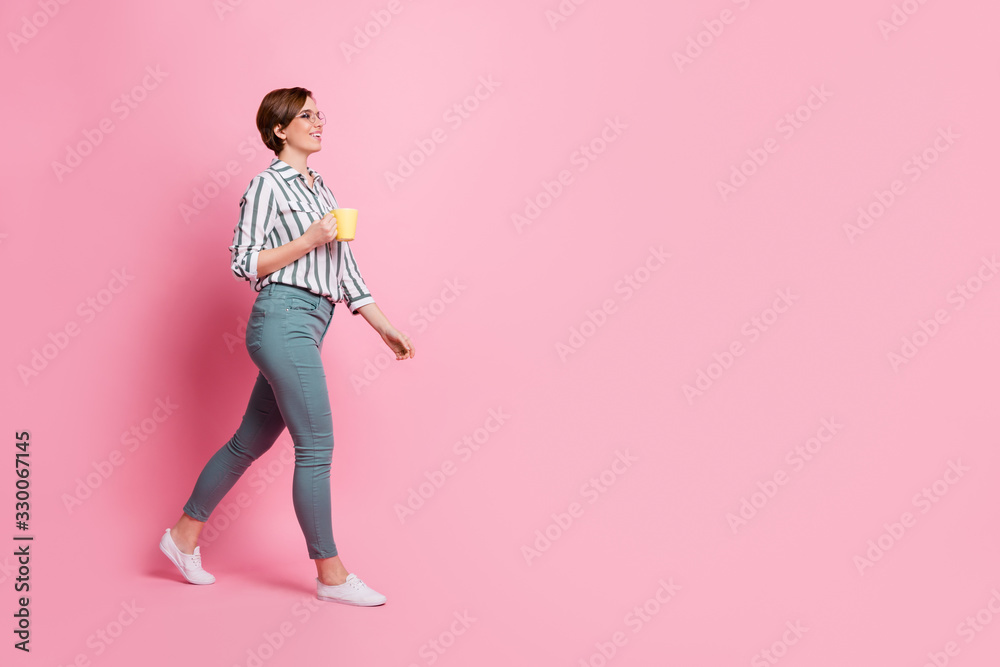 Full length profile side photo of positive assistant girl hold yellow espresso beverage cup bring to her boss freelancer entrepreneur wear modern outfit isolated over pink color background Full length profile side photo of positive assistant girl hold yellow espresso beverage cup bring to her boss freelancer entrepreneur wear modern outfit isolated over pink color background