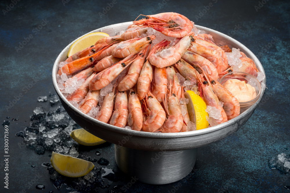 A lot of shrimp with lemon in an iron dish