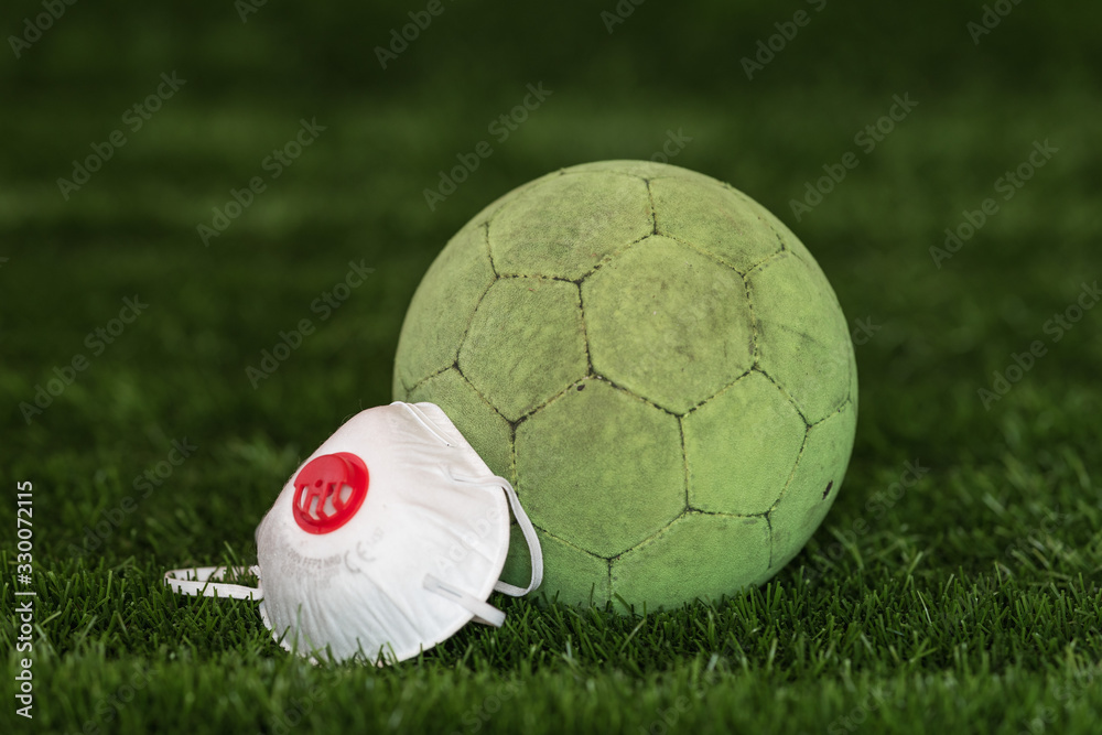 Naklejka premium The soccer ball with face mask as a symbol coronavirus