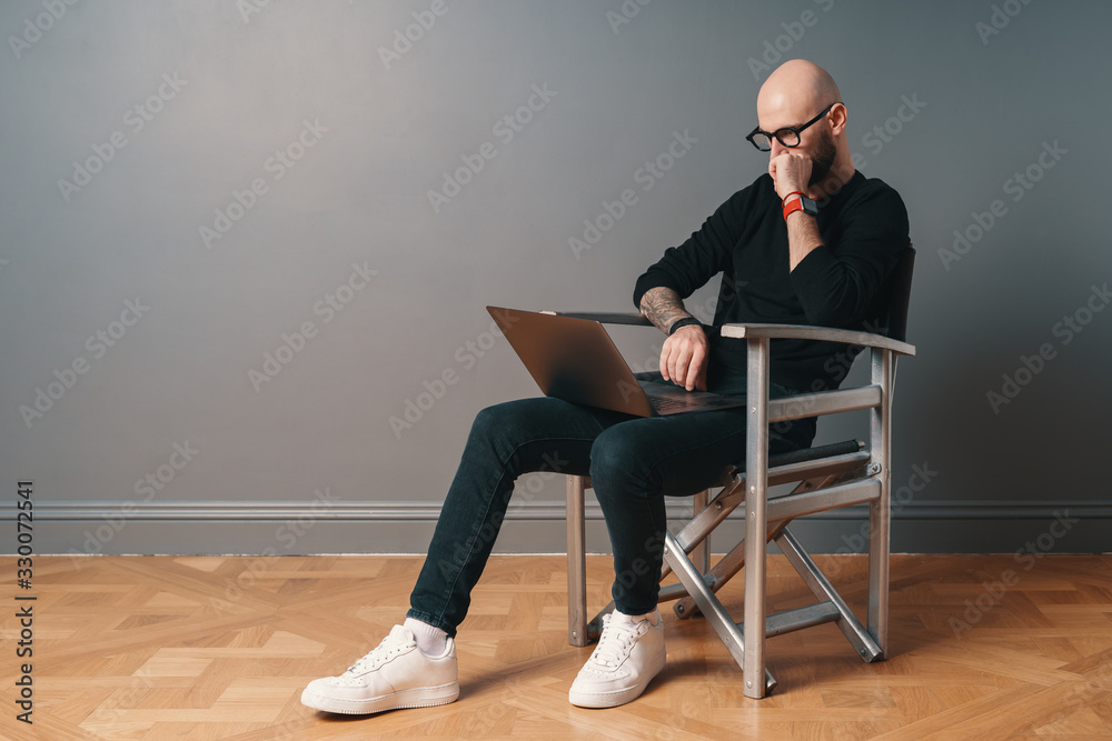 Modern young caucasian man with beard and glasses relaxing while surfing internet on laptop pc Modern young caucasian man with beard and glasses relaxing while surfing internet on laptop pc