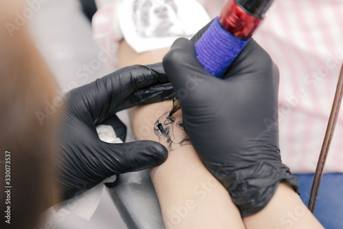 A ttattoo artist drawing a dog in a womans arm