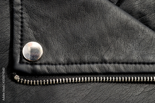 Fragments of a black artificial leather jacket with rivets and zippers. Background for clothes and metal accessories.