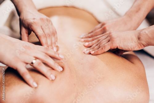4 hands massage - two masseurs work simultaneously on the patient back - effective therapeutic massage