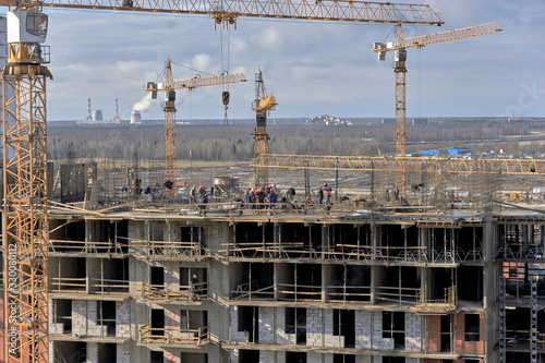 A lot of builders in helmets and masks on the top floor of a house under construction