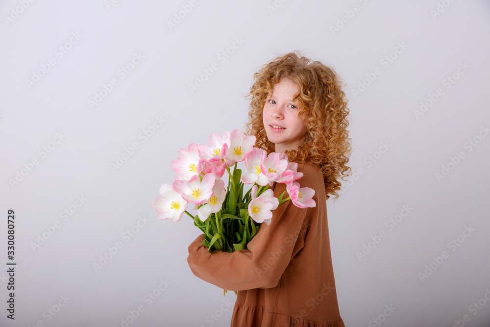 beautiful red haired curly haired teen girl with a bouquet of spring pink tulips on a white background beautiful red haired curly haired teen girl with a bouquet of spring pink tulips on a white background