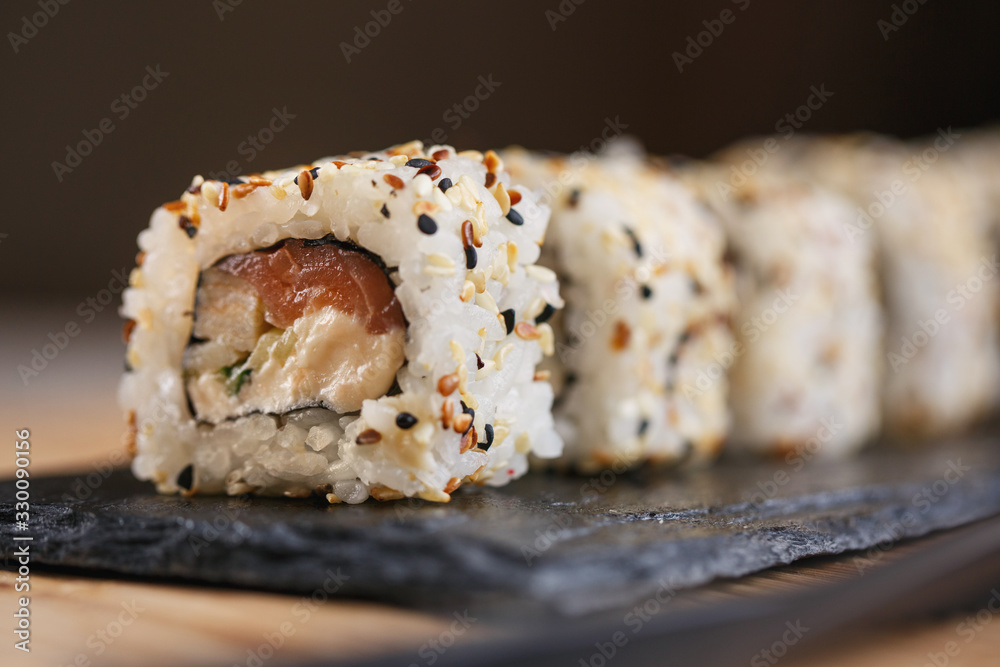 Sushi roll with salmon, eel, cucumber, cream cheese and sesame on a black board. Japanese food. Sushi roll with salmon, eel, cucumber, cream cheese and sesame on a black board. Japanese food.