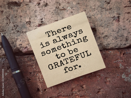 Motivational and inspirational wording. There Is Always Something To Be Grateful For written on an adhesive note. Vintage styled background. photo