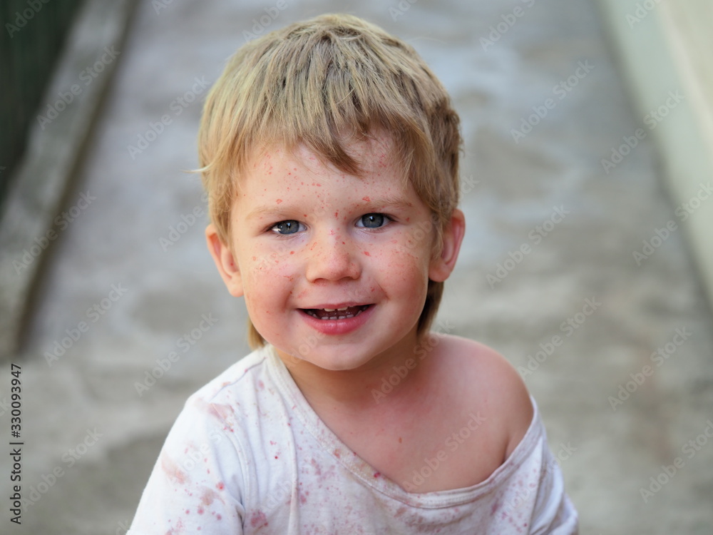 A smiling child is splattered with juice. The village fair haired boy smiled happily A smiling child is splattered with juice. The village fair haired boy smiled happily