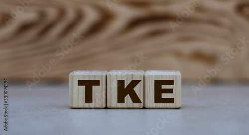 concept of the word TKE on cubes on a gray background with letters photo