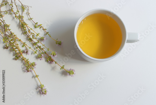 Healthy herbal tea with bunch of fresh wild thyme on old wooden background. Cup of thyme tea, herbal drink.