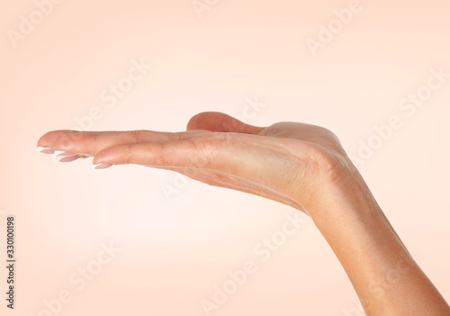 Closeup shot of female hand on peach colored background