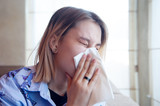 Girl sneezing feeling sick. Female blowing her nose in the hospital. Coronavirus covid-19