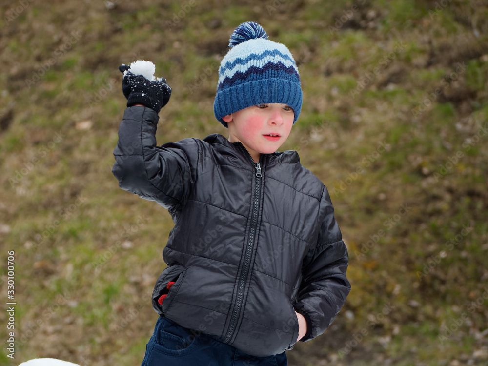winter fun. cheerful child in a hat plays snowballs winter fun. cheerful child in a hat plays snowballs