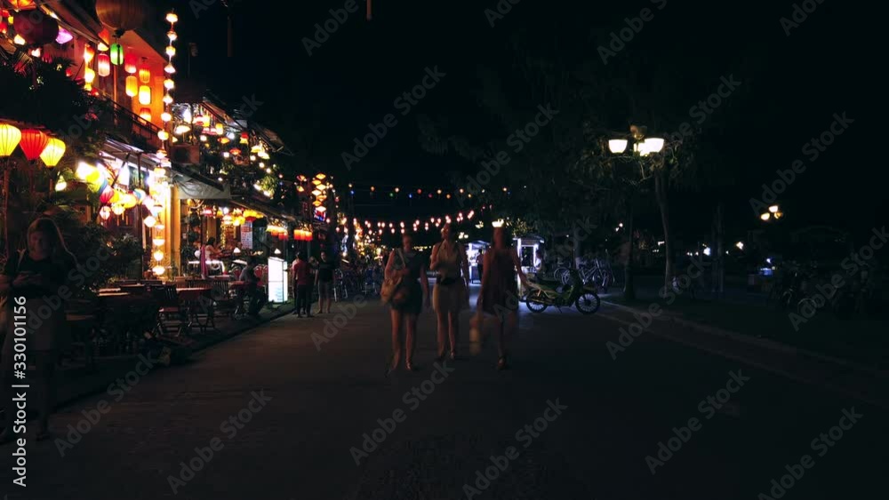 Hoi An, Quang Nam, Vietnam - March 8, 2020: Timelapse. People tourists walking in oldt ancient town Hoi An near river Thu Bon, chinese traditional lanterns decorates cafes and restaurants. UNESCO Worl Hoi An, Quang Nam, Vietnam - March 8, 2020: Timelapse. People tourists walking in oldt ancient town Hoi An near river Thu Bon, chinese traditional lanterns decorates cafes and restaurants. UNESCO Worl