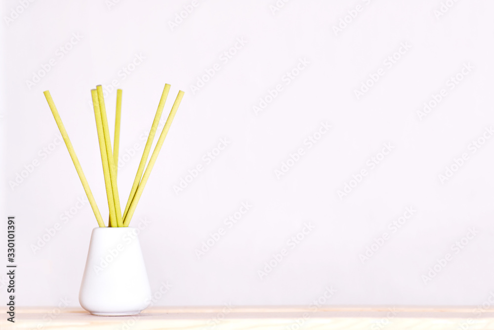 Aroma diffuser with reed sticks in a white bottle on a light purple background Aroma diffuser with reed sticks in a white bottle on a light purple background