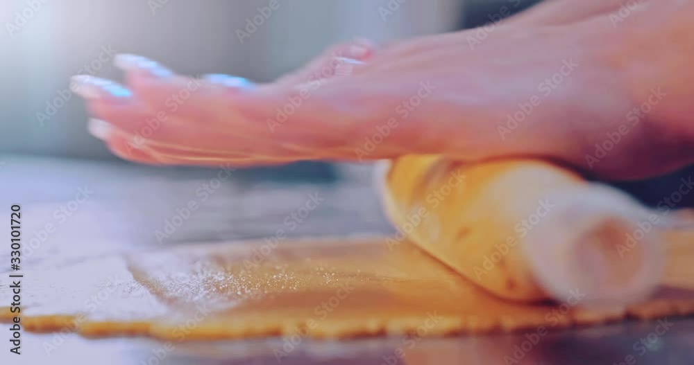 Woman rolls out the dough on the kitchen table. Female hands rolling dough with a rolling pin, macro. Hostess cooking food at home. Women hands roll a dough rolling pin. Slow motion 4k footage Woman rolls out the dough on the kitchen table. Female hands rolling dough with a rolling pin, macro. Hostess cooking food at home. Women hands roll a dough rolling pin. Slow motion 4k footage
