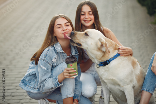 Beautiful girls drinking a coffee. Women in a spring city. Ladies with cute dog. © hetmanstock2
