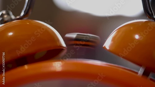 Close up of retro alarm clock going off on blurred background. Stock fooatge. Orange alarm clock details for waking up in the morning.