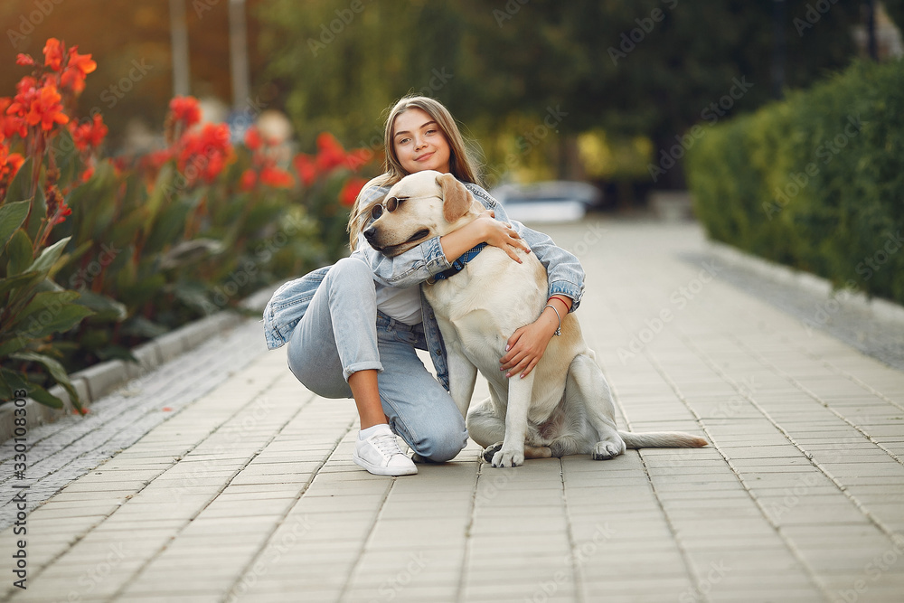 Fototapeta premium Beautiful girl in a park. Stylish girl in a jeans jacket. Lady with a dog