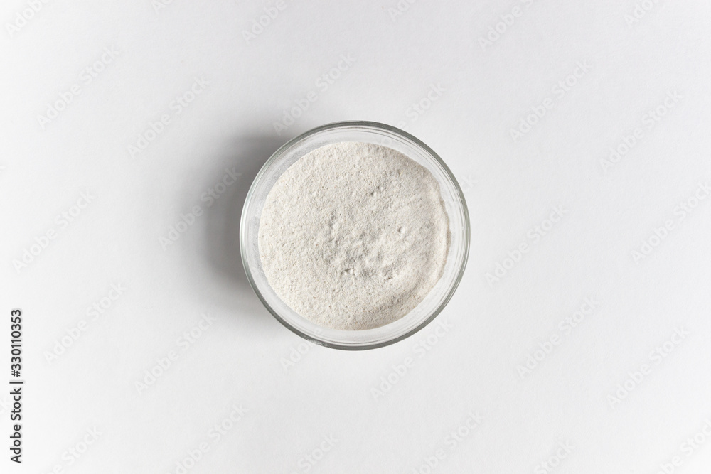 Powder of green buckwheat in glass bowl on white background Powder of green buckwheat in glass bowl on white background