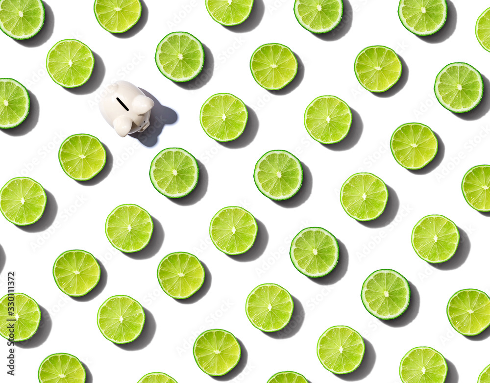 One out unique piggy bank surrounded by limes - flat lay