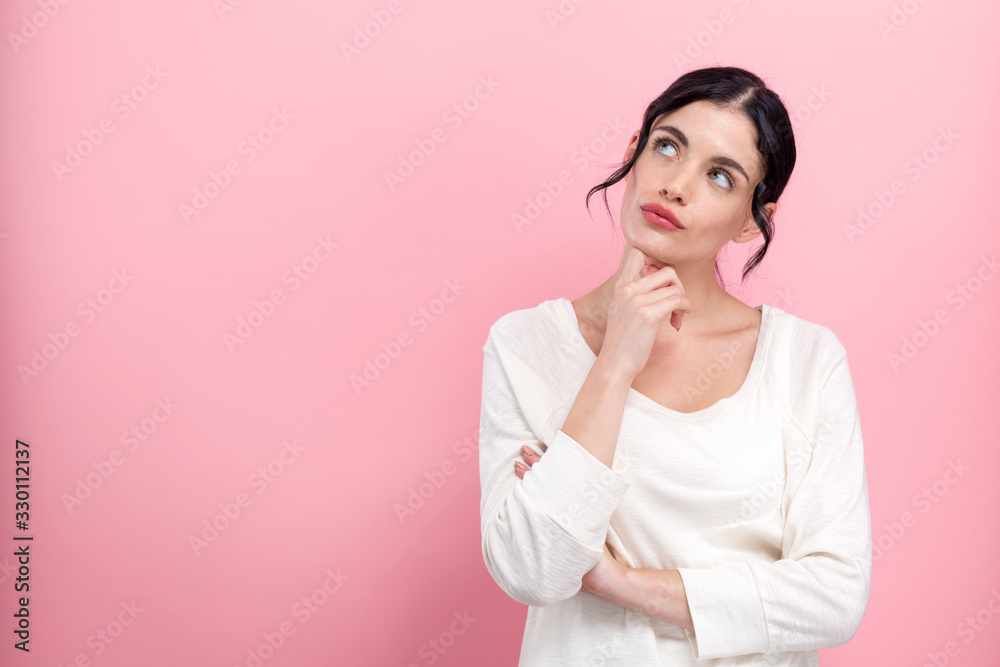 Young woman in a thoughtful pose on a pink background Young woman in a thoughtful pose on a pink background