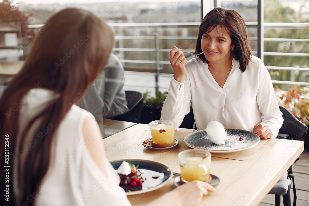 Beautiful women in a cafe. Mother with daughter at the table. Lady in a white shirt. Beautiful women in a cafe. Mother with daughter at the table. Lady in a white shirt.