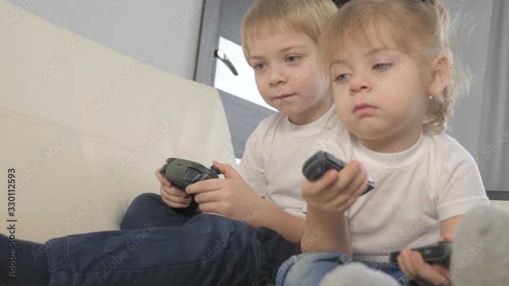 children lifestyle a play console in gamepads teamwork. kids boy and girl are playing portable set-top box in TV controller. happy family little boy and girl have online fun games children lifestyle a play console in gamepads teamwork. kids boy and girl are playing portable set-top box in TV controller. happy family little boy and girl have online fun games